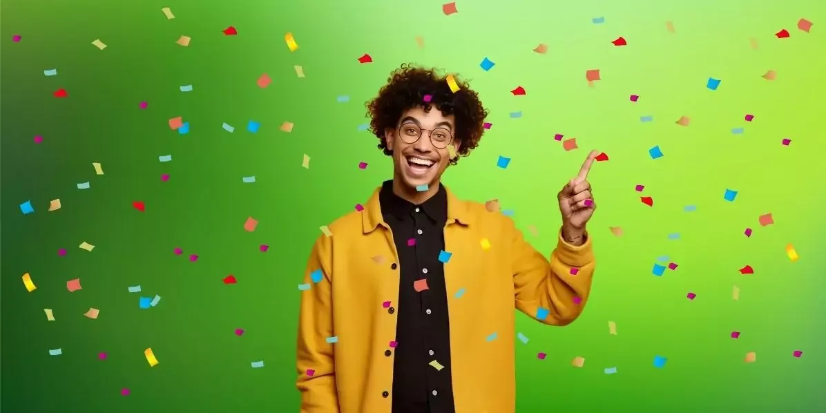 Hombre celebrando con los puños cerrados sobre un fondo verde con papel picado de colores cayendo.